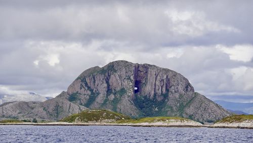 Scenic view of sea by mountain against sky