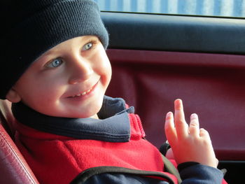 Close-up of smiling boy looking away while traveling in bus