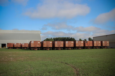 Vehicle trailers on grassy field against sky