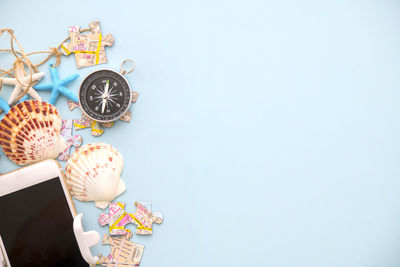 High angle view of compass with mobile phone and puzzle on blue background