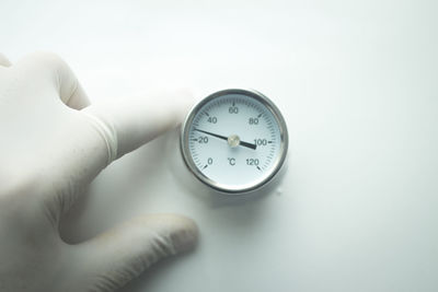 Cropped hand by oxygen pressure gauge over white background