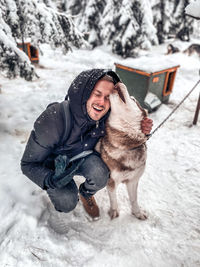 Portrait of woman with dog on snow covered field