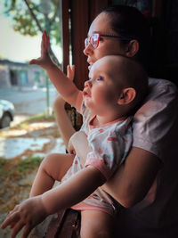 Mother peeks her daughter out the window to greet the leaves that fall in the fall during quarantine