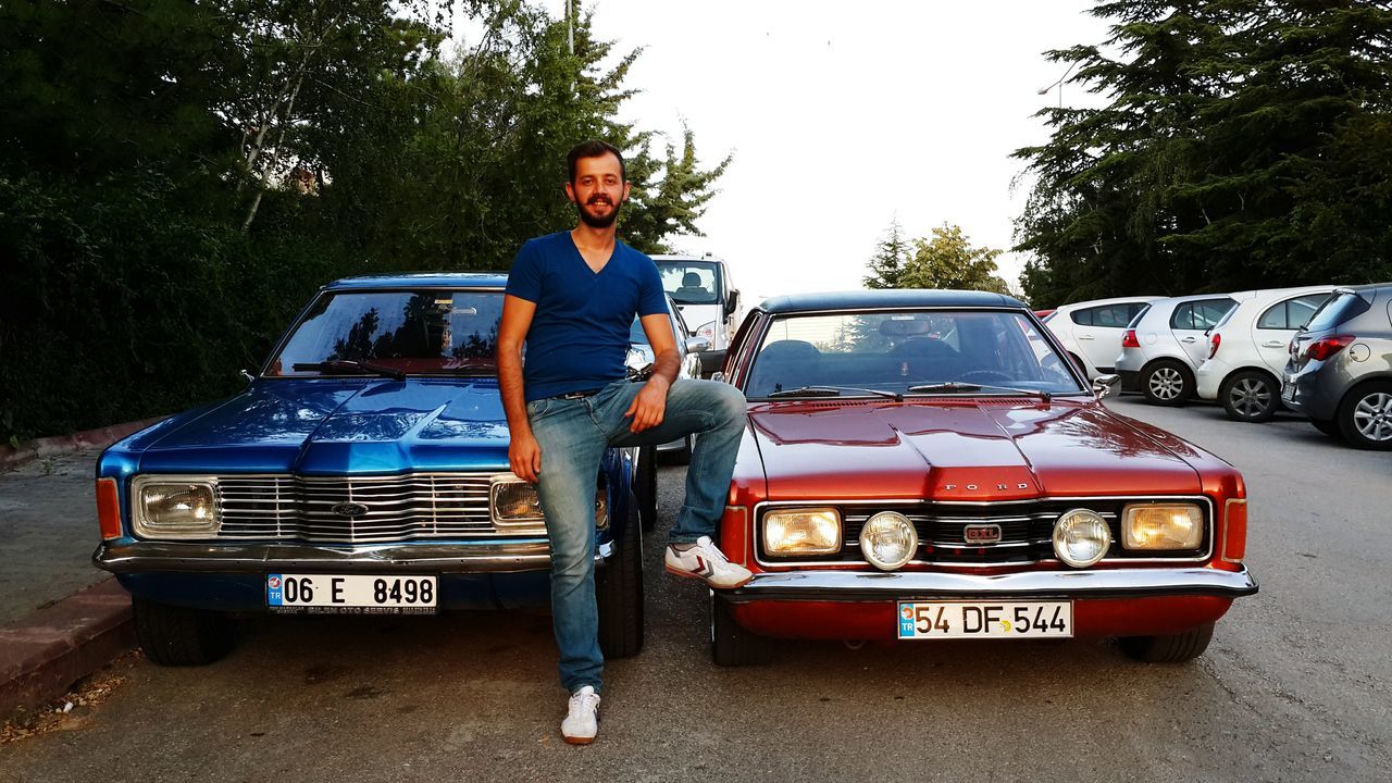 transportation, lifestyles, mode of transport, full length, land vehicle, leisure activity, car, casual clothing, young adult, street, travel, side view, men, person, front view, sitting, day, holding