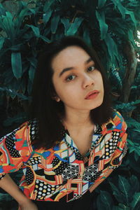 Portrait of beautiful young woman against tree