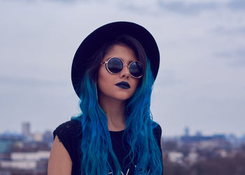 Close-up portrait of woman wearing sunglasses against sky