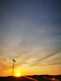 Low angle view of silhouette vapor trail against sky during sunset