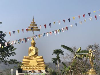 Low angle view of statue against temple building against clear sky