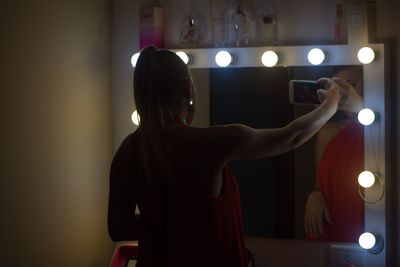 Rear view of woman standing in illuminated room