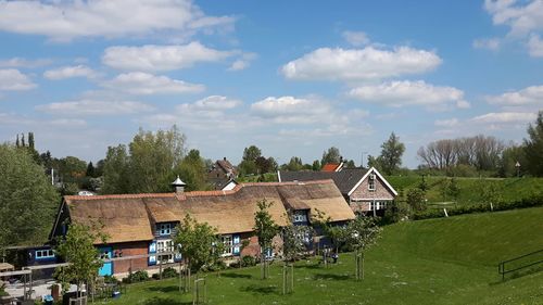 Houses and trees on field against sky