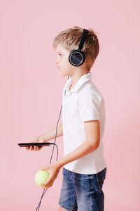 Full length of boy holding umbrella standing against wall