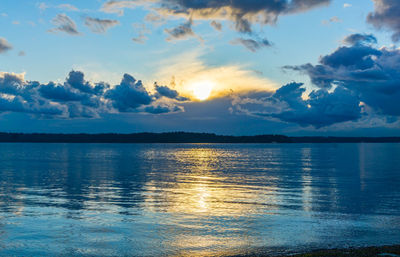 The sun is setting in a cloudy sky at lincoln park in west seattle, washington.