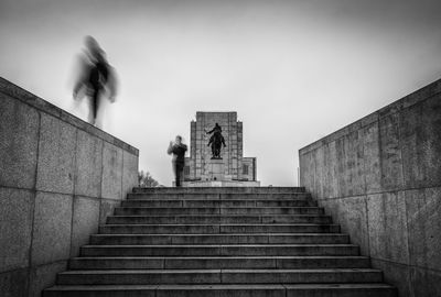 Blurred motion of people by steps against sky