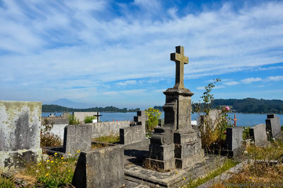 Cross at cemetery against sky