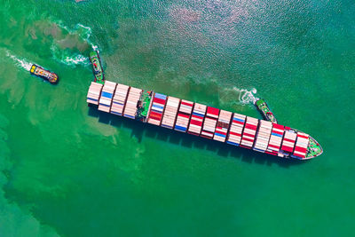 Aerial top view of ocean cargo ship with contrail in ocean ship carrying containers.