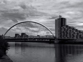 Bridge over river against cloudy sky