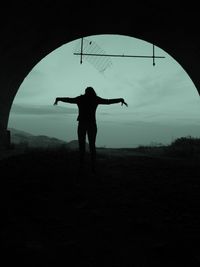 Rear view of silhouette man standing on field against sky