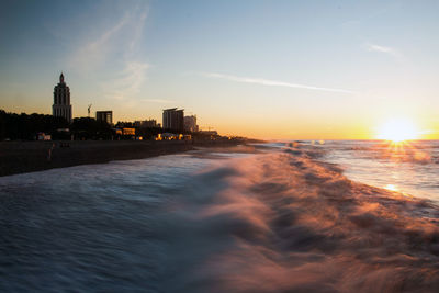 Scenic view of sea and buildings against sky during sunset
