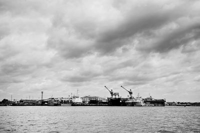 Cranes at commercial dock against sky