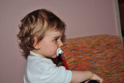 Cute baby boy sucking pacifier at home