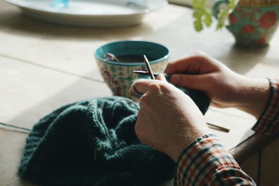 Close up of young man knitting at home