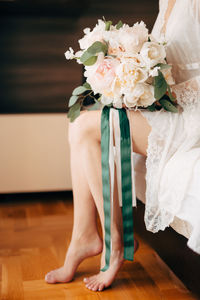 Low section of woman standing on white rose