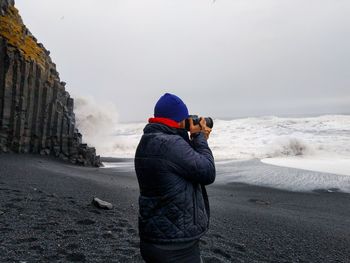 Man photographing while standing at beach