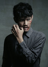 Thoughtful injured young man standing against wall