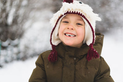 Cute little boy in funny winter hat walks during a snowfall. outdoors winter activities for kids.