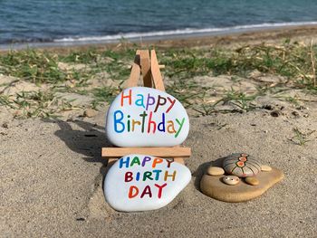 Unique happy birthday message with a creative composition of carved stones on the beach 