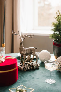 Christmas decor of a festive table with a statuette of a deer and a glass