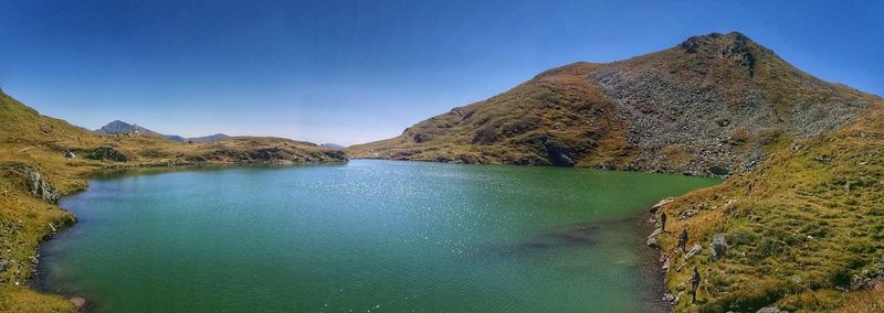 Scenic view of lake and mountains against clear blue sky