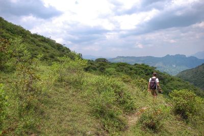 Rear view of people walking on mountain against sky