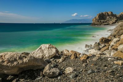 Rocky sea shore against blue sky