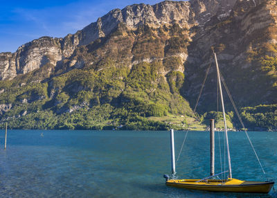 Boat sailing on sea by mountain against sky