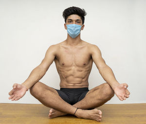 Full length of shirtless man looking away against white background