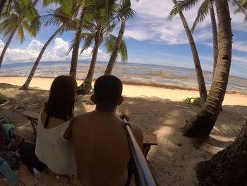 Rear view of people sitting on beach