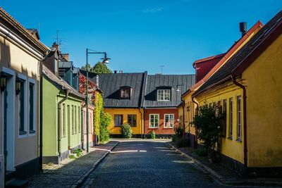 Road amidst houses against sky