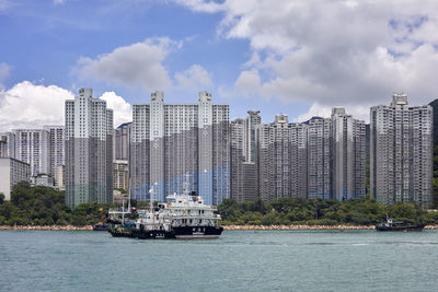 Sailboats in sea against modern buildings in city