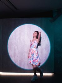 Full length of smiling young woman standing against wall