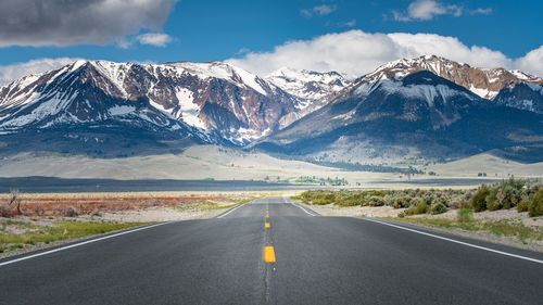 Road amidst snowcapped mountains against sky