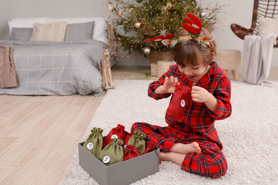 Girl playing with christmas tree at home