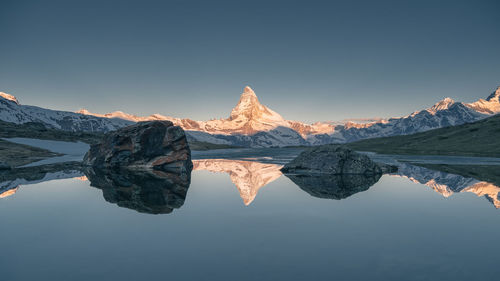 Reflection of mountain in lake against clear sky during winter