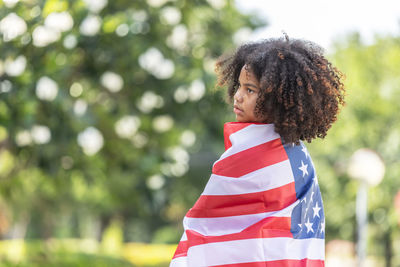 Girl wrapped in american flag outdoors