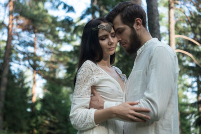 Young couple standing against trees