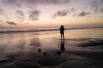 People standing on beach at sunset