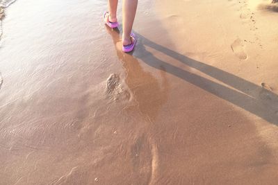 Low section of woman standing on sand at beach