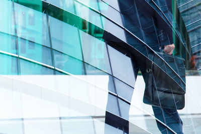 Low section of man standing by glass building