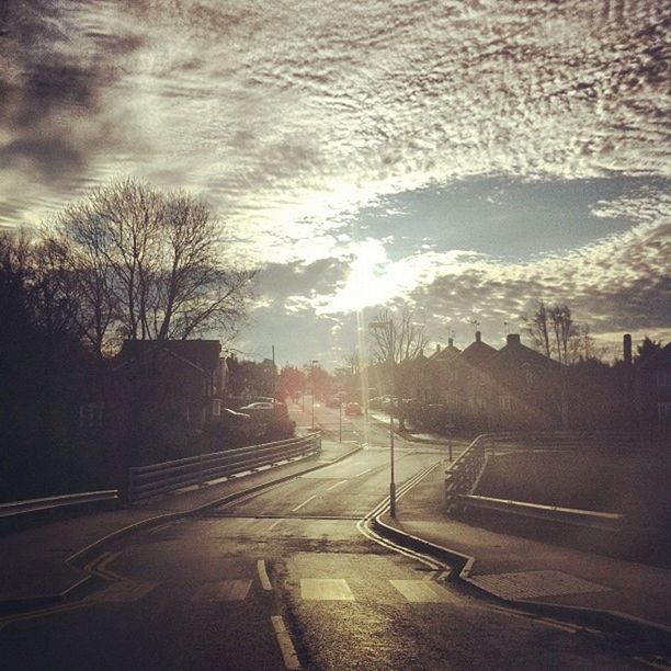 road, transportation, sun, sky, street, sunset, car, building exterior, sunlight, city, cloud - sky, tree, the way forward, sunbeam, built structure, silhouette, land vehicle, lens flare, architecture, nature