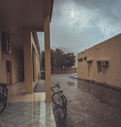 Wet street amidst buildings against sky during rainy season